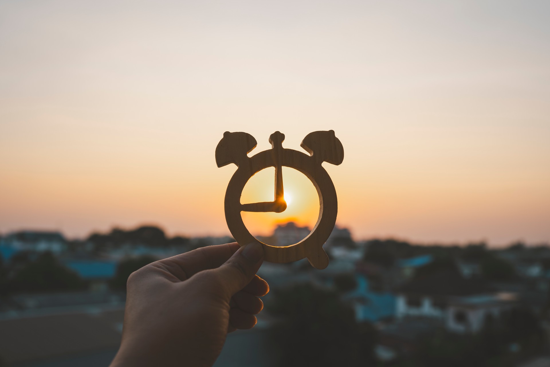 Hand holding the time symbol with sun set  background. time to relax and autumn season concepts.